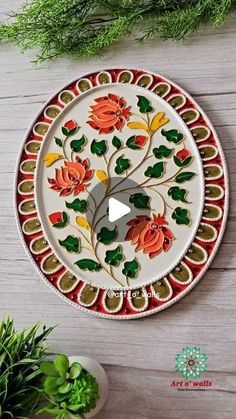 a white plate with flowers painted on it next to some green plants and a potted plant