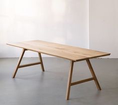 a wooden table sitting on top of a cement floor next to a white wall in an empty room