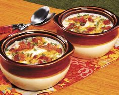 two bowls of food on a table with spoons next to it and an orange place mat