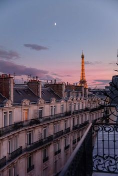 the eiffel tower is seen in the distance from an apartment building at sunset