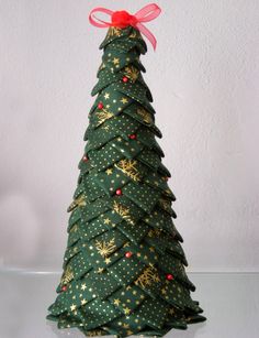 a green christmas tree with gold stars and red bows on it's top, sitting on a table