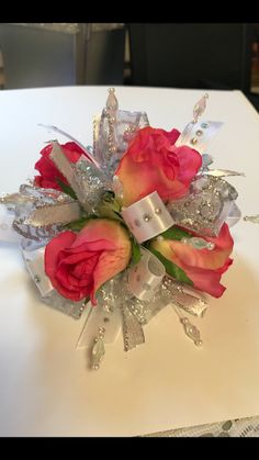 a bouquet of flowers on top of a white table with silver ribbon and bow around it