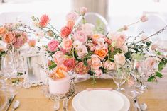 the table is set with pink and orange flowers, silverware, and candlesticks