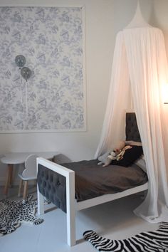 a bed with a white canopy over it in a room filled with zebra rugs