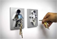 someone is holding two keys in front of the wall mounted key holders that are attached to each other