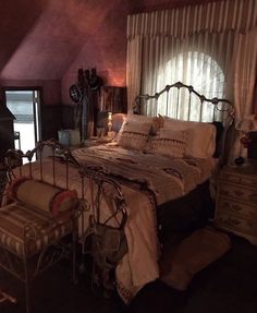 a bedroom with a bed, dressers and window in the corner that has curtains on it