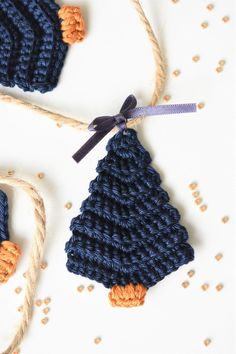 two crocheted christmas trees are hanging from twine strings on a white surface