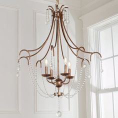 a chandelier hanging from the ceiling in a room with white walls and windows