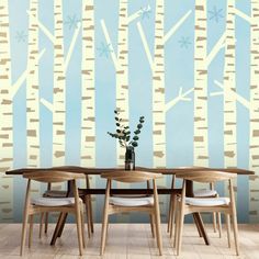 a dining room table with four chairs in front of a wall painted with birch trees