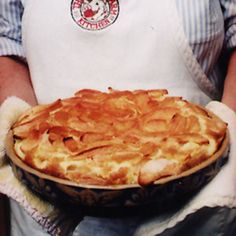 a person wearing an apron holding a pie