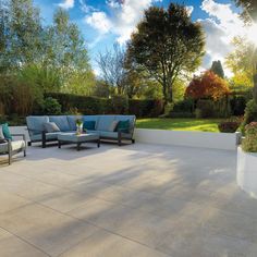 an outdoor patio with blue couches and white planters on the side, surrounded by greenery