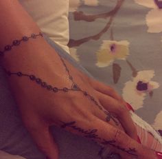 a woman's hand with a rosary tattoo on her left wrist and the word love is written in cursive writing