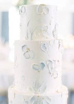 a three tiered white wedding cake with blue flowers