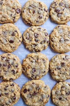 chocolate chip cookies are lined up on a sheet of parchment paper, ready to be eaten