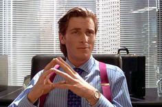 a man sitting in an office chair making the v sign with his hands while wearing a tie and suspenders