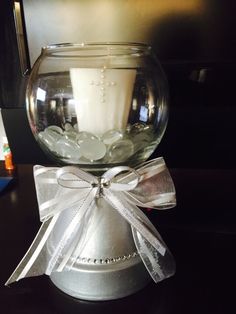 a candle in a glass bowl with a bow around it on top of a table