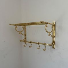 a gold shelf with hooks on it against a white wall