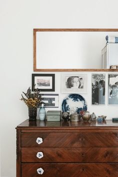 a dresser and mirror with pictures on the wall