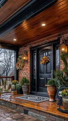 a porch with potted plants and lights on the front door, surrounded by brick pillars