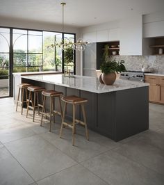 a kitchen with an island and stools next to the counter top in front of a large window