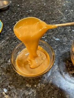 a spoon full of peanut butter sitting on top of a counter next to another bowl