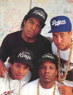 three young men posing for the camera with chains on their neck and one wearing a hat