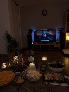 a table topped with food and candles next to a tv screen in the background,