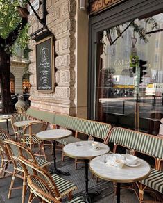 tables and chairs are lined up on the sidewalk in front of a storefront window