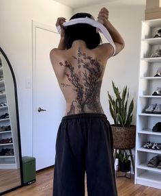 a man with tattoos on his back standing in front of a closet