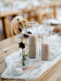 two vases filled with flowers on top of a wooden table covered in white cloth