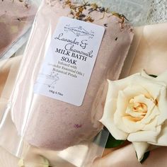 there is a pink bath soak next to a white rose