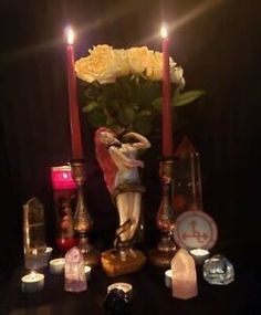 a table topped with candles and figurines next to flowers