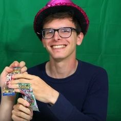 a young man wearing glasses and a pink party hat holding up some candy bar wrappers