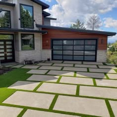 a large house with grass on the front lawn and two car garages behind it