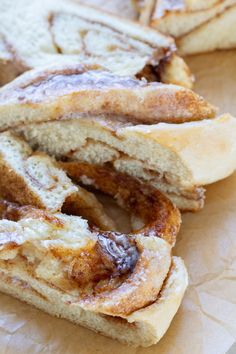 cinnamon roll sitting on top of a piece of wax paper next to other pastries