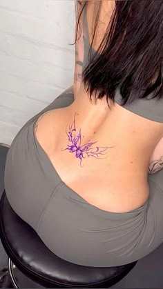 the back of a woman's stomach with a tattoo on her left side and purple flowers