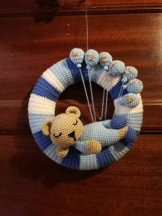 a blue and white crocheted wreath with a teddy bear hanging from it