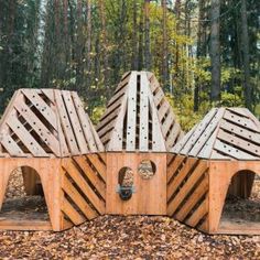 several wooden structures in the woods with leaves on the ground