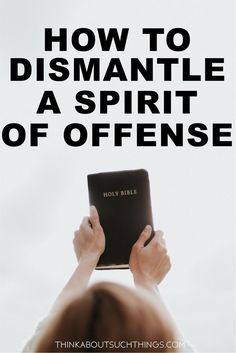 a person holding up a book with the title how to dismantle a spirit of offense