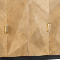 a wooden cabinet with two brass handles and geometric designs on the doors, in front of a white background