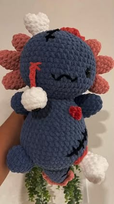 there is a crocheted stuffed animal that looks like a monster with horns and tail