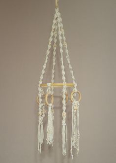 a white macrame hanging from a hook with gold rings and tassels