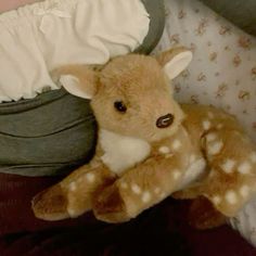 a stuffed deer laying on top of a bed next to a baby's diaper