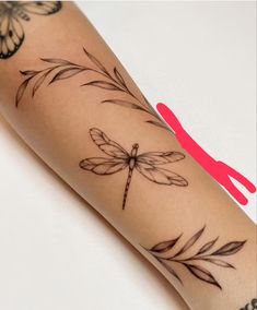 a woman's arm with a dragonfly tattoo on it