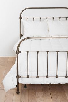 a metal bed with white pillows on top of it