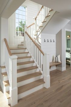 there is a white staircase with wood handrails in the room and windows on the wall