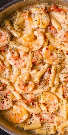 a pan filled with pasta and shrimp covered in sauce, garnished with parsley