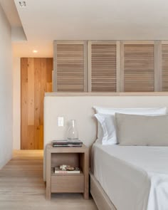 a white bed sitting next to a wooden wall