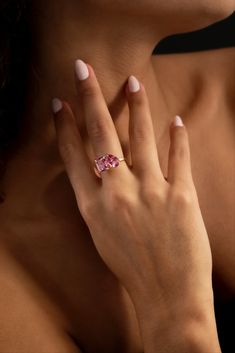 a woman's hand with a pink ring on her left wrist and white nails