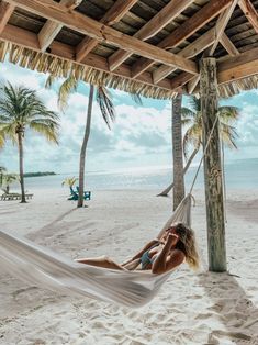 a woman laying in a hammock on the beach